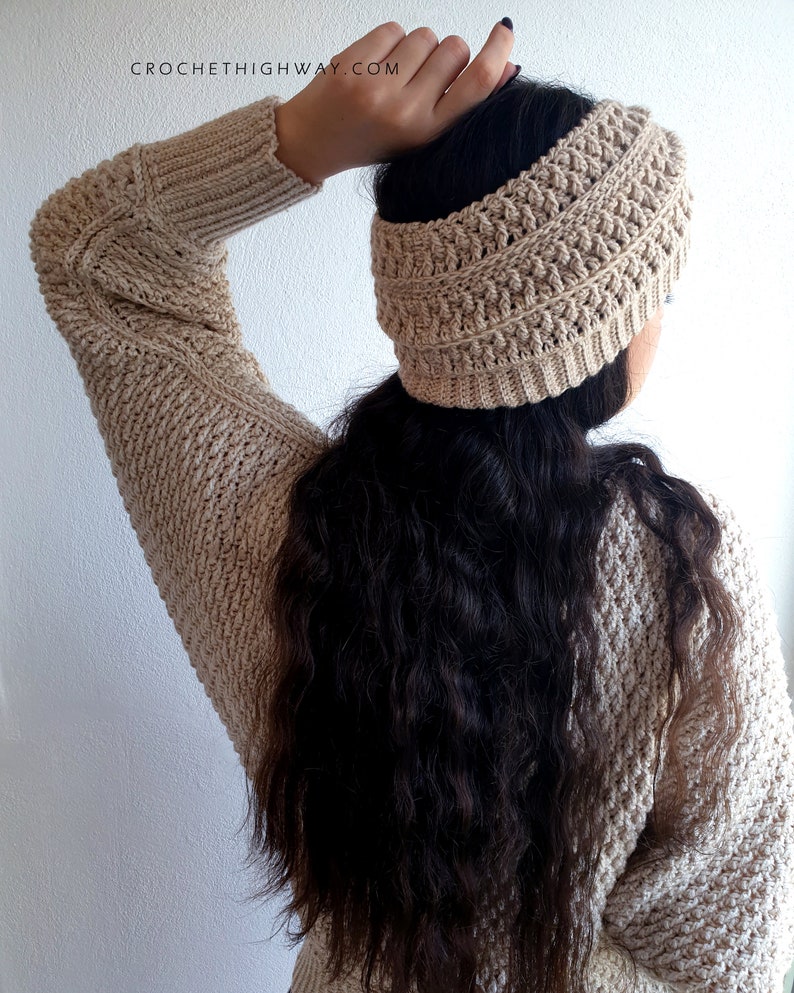 May include: A beige crochet headband with a textured pattern. The headband is worn by a person with long, dark hair.