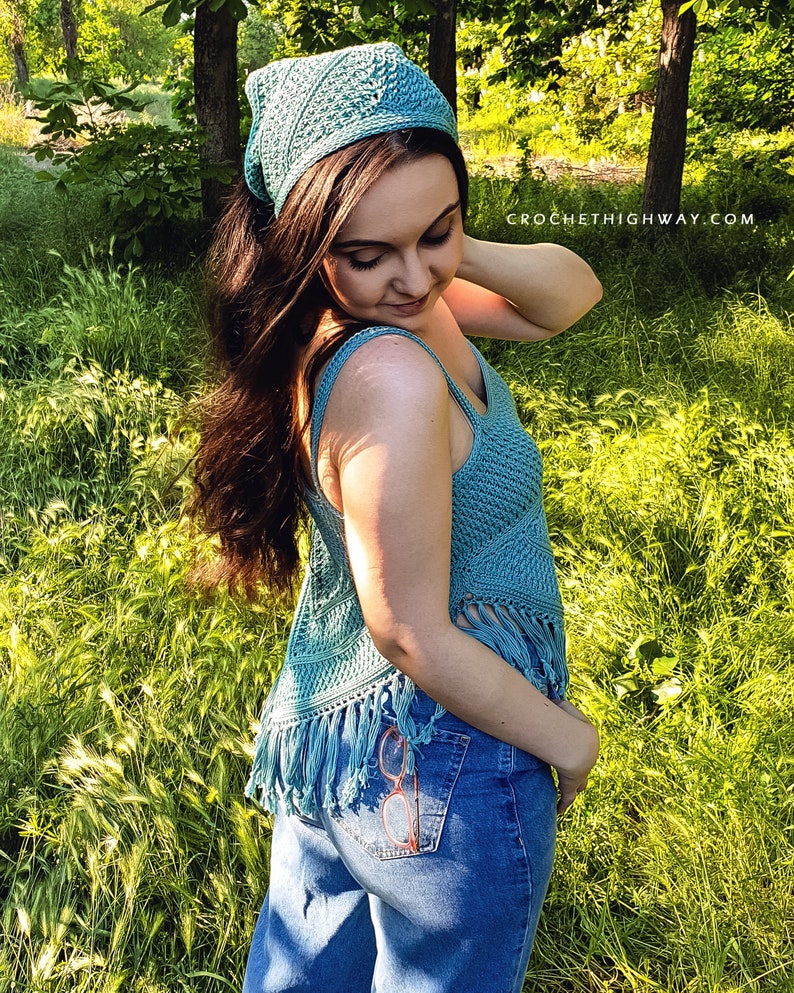 Puede incluir: Una mujer lleva una blusa de crochet azul con detalles de flecos y una bandana de crochet azul. Lleva unos vaqueros azules con un par de gafas bordadas en el bolsillo trasero. La foto fue tomada al aire libre en una zona cubierta de hierba.