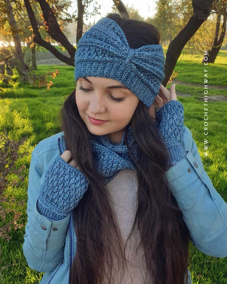 May include: A blue crocheted headband, neck warmer, and fingerless gloves set. The headband has a knot on top. The set is made with a textured stitch.