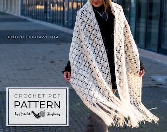 May include: A white crochet shawl with fringe, worn by a person with a black shirt. The shawl has a delicate floral pattern. The text "CROCHETHIGHWAY.COM" is visible in the background. The text "CROCHET PDF PATTERN by Crochet Highway" is visible in the foreground.