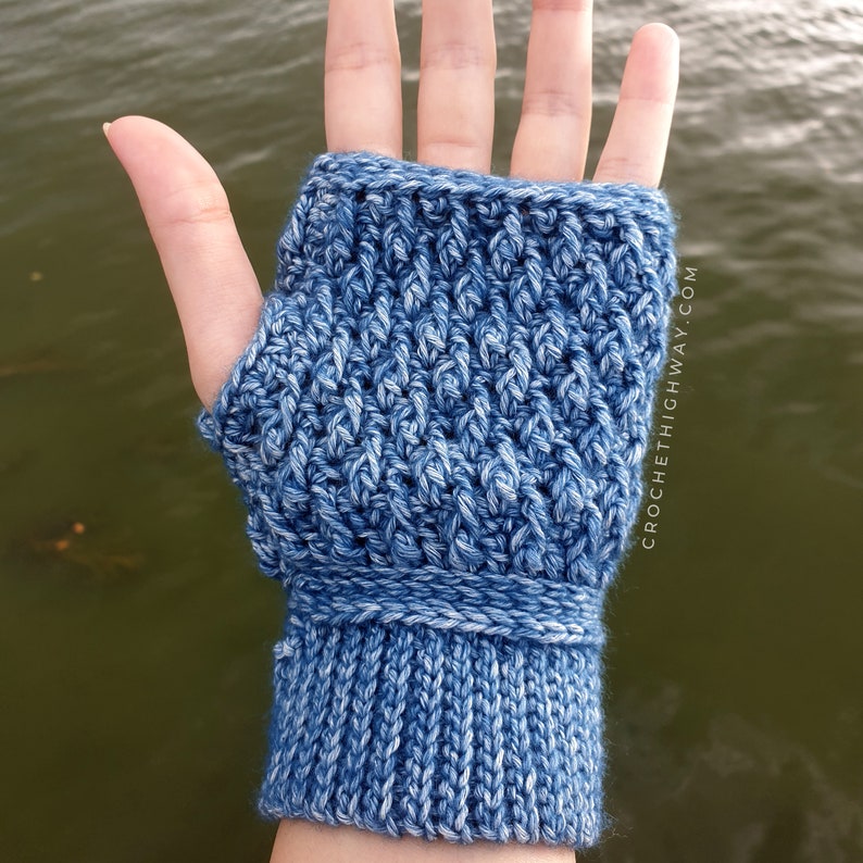 May include: Blue and white crocheted fingerless gloves with a ribbed cuff. CROCHETHIGHWAY.COM is printed on the side of the glove.
