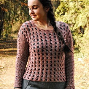 K&ouml;nnte beinhalten: Ein geh&auml;kelter Pullover mit geometrischem Muster in einem staubigen Rosaton. Der Pullover hat eine lockere Passform und lange &Auml;rmel. Der Pullover wird von einer Person in einer nat&uuml;rlichen Umgebung getragen.