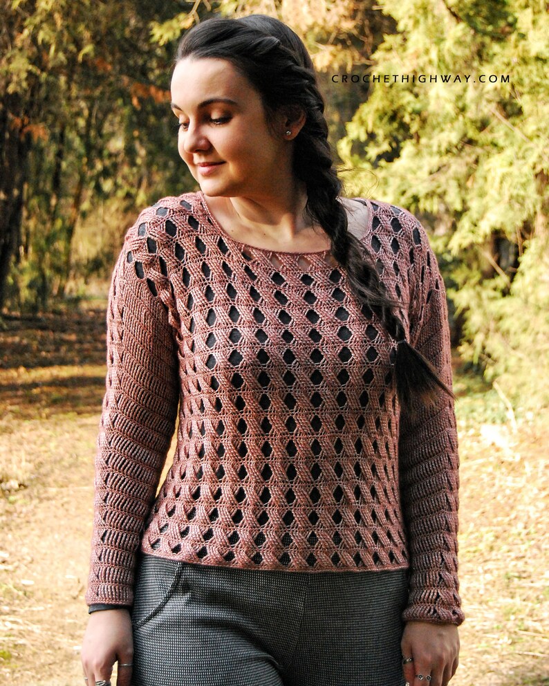 K&ouml;nnte beinhalten: Ein geh&auml;kelter Pullover mit geometrischem Muster in einem staubigen Rosaton. Der Pullover hat eine lockere Passform und lange &Auml;rmel. Der Pullover wird von einer Person in einer nat&uuml;rlichen Umgebung getragen.