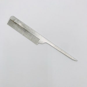 May include: A silver comb with a long, thin handle. The comb has fine teeth and a pointed tip.
