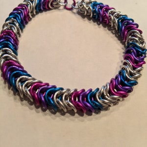 May include: A silver, blue and pink chainmail bracelet with a silver clasp.