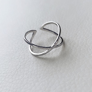 May include: A silver ring with a simple, modern design. The ring is made of two thin bands that cross over each other.