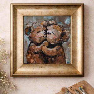 Peut inclure: Peinture à l'huile encadrée en or représentant deux ours en peluche bruns s'embrassant et s'embrassant. L'œuvre d'art a un style doux et pictural avec des coups de pinceau visibles. L'arrière-plan est bleu et gris. Une palette et des pinceaux sont au premier plan.