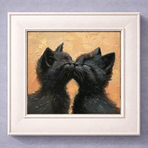 May include: A framed painting depicts two black cats kissing, their faces touching. The artwork is set against a textured, golden-yellow background. The cats' fur is detailed, and the painting is encased in a white frame.