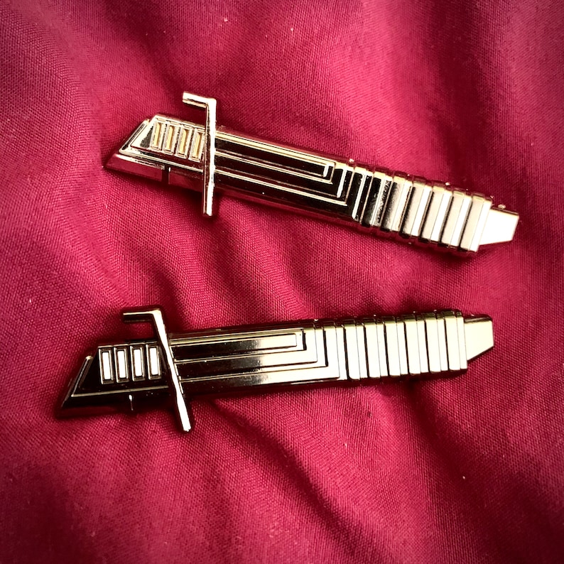 May include: Two gold-colored metal lightsaber toys. The lightsabers have a detailed design with a series of lines and ridges.