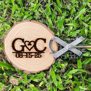 May include: A wooden wedding keepsake with the initials "G&C" and a heart symbol, along with the date "08-15-25" engraved on a wood slice. A metal branding iron with the numbers "5487" is also visible.