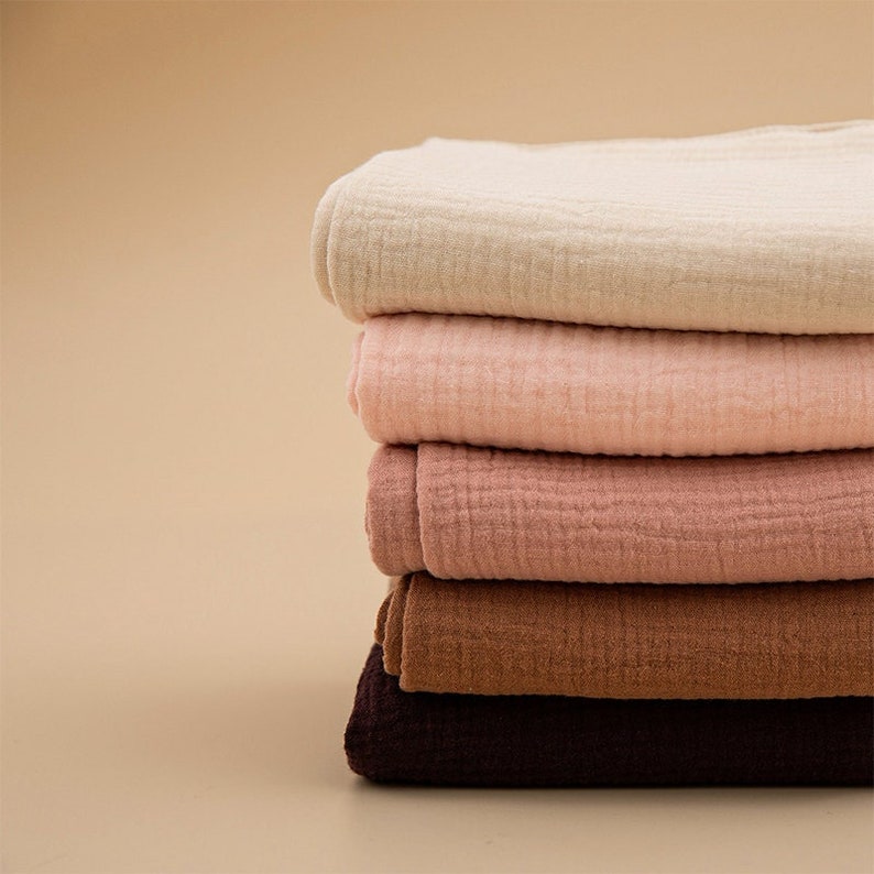 May include: A stack of five fabric squares in different shades of brown, pink, and beige. The fabric is a soft, gauzy material with a slightly textured surface.