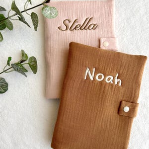 May include: Two personalized baby blankets, one pink with the name "Stella" embroidered on it and one brown with the name "Noah" embroidered on it.