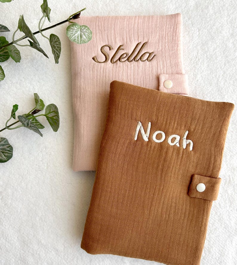 May include: Two personalized baby blankets, one pink with the name "Stella" embroidered on it and one brown with the name "Noah" embroidered on it.