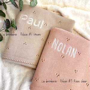 May include: Two personalized baby blankets, one beige with the name "Paul" and the text "La broderie: Police #1 Ivoire" and one pink with the name "NOLAN" and the text "La broderie Police #5 Rose clair".