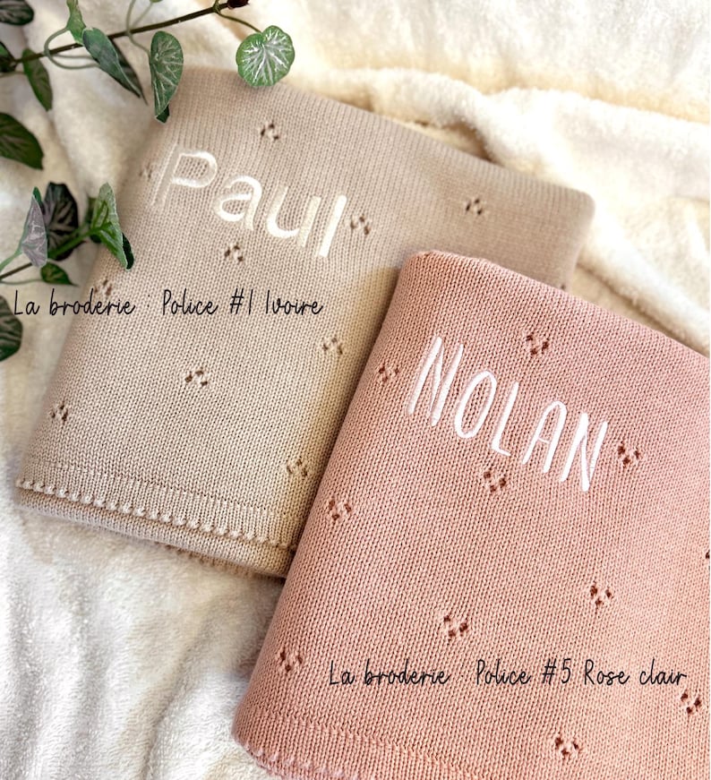 May include: Two personalized baby blankets, one beige with the name "Paul" and the text "La broderie: Police #1 Ivoire" and one pink with the name "NOLAN" and the text "La broderie Police #5 Rose clair".