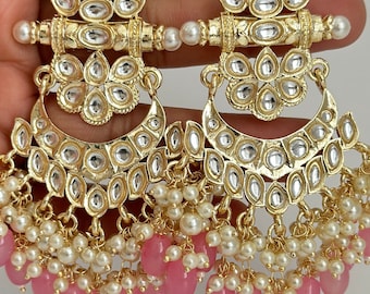 May include: Gold earrings with pink and white beads. The earrings feature a crescent moon design with intricate details and a floral top.