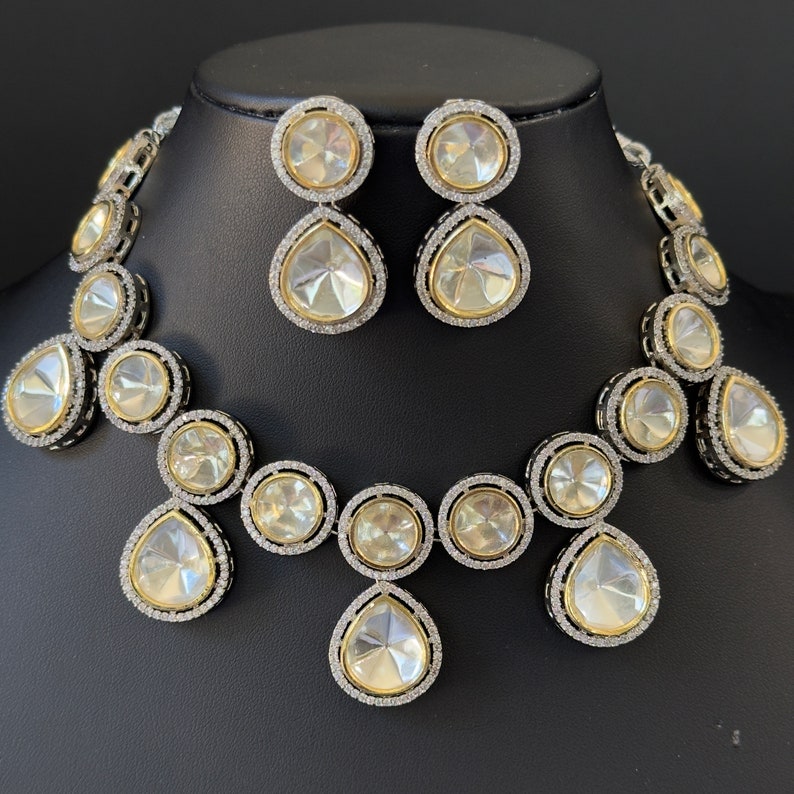 May include: A silver and white teardrop-shaped necklace and earrings set with large, clear stones. The necklace features a cascading design with multiple teardrop-shaped stones.