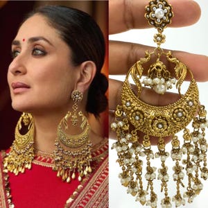 May include: A pair of large, gold-tone earrings with pearl accents. The earrings feature a crescent moon shape with intricate floral designs and dangling pearl chains.
