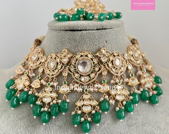 May include: A gold and silver necklace with green and white beads. The necklace has a large, ornate pendant in the center.