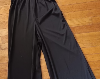 May include: A black jumpsuit with a wide-leg silhouette and a rhinestone belt. The jumpsuit has a deep V-neckline and a halter-style top.