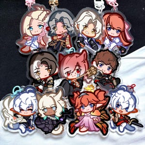 Puede incluir: Una colección de coloridos colgantes acrílicos con personajes de estilo anime. Cada colgante tiene un diseño único con colores vibrantes y obras de arte detalladas. Los colgantes están unidos a llaveros con herrajes rosas y dorados.