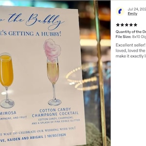 Pu&ograve; includere: Un cartello nuziale bianco con testo blu che recita Pop the Bubbly, She's getting a hubby! Presenta illustrazioni di una mimosa gialla e un cocktail allo champagne con zucchero filato rosa. Il testo in basso recita Love, Kaiden and Abigail.