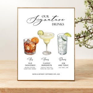 Pu&ograve; includere: Un cartello rettangolare con cornice dorata che presenta il testo "OUR SIGNATURE DRINKS" sopra le illustrazioni di un Old Fashioned, un Margarita classico e un Gin Tonic. Sotto le bevande ci sono etichette e "MAYRA & ANTHONY | SEPTEMBER 18TH, 2025".