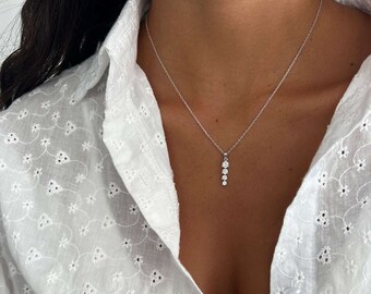 May include: A silver chain necklace with a pendant featuring a row of five small, clear gemstones.