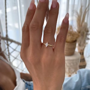 May include: A gold ring with a single, clear marquise-shaped gemstone.