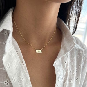 May include: A gold chain necklace with a small rectangular pendant featuring a diamond-encrusted Star of David.