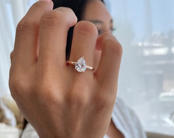 May include: A rose gold ring with a pear-shaped clear gemstone.