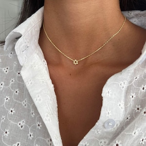 May include: A gold chain necklace with a small, delicate Star of David pendant.