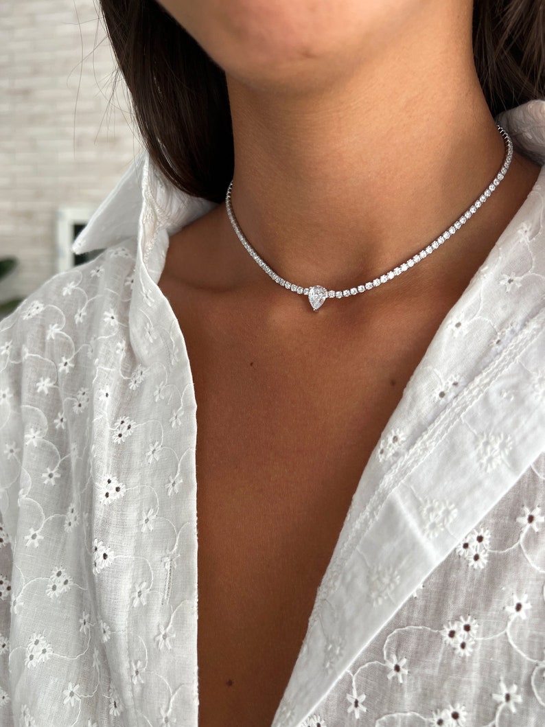 Peut inclure: Un collier ras de cou argent&eacute; avec un pendentif en diamant de forme poire.