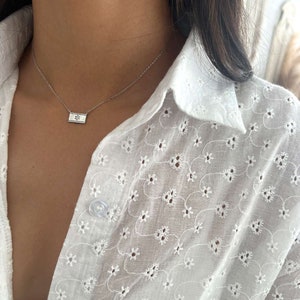 May include: A silver chain necklace with a small rectangular pendant featuring a silver Star of David.