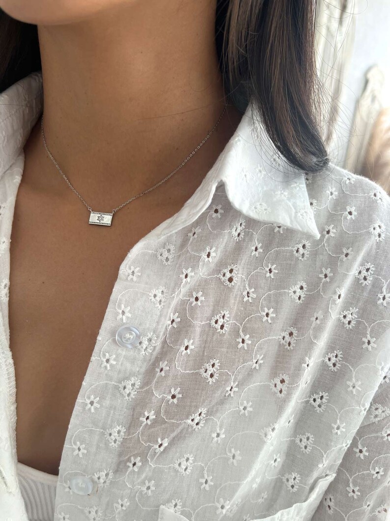 May include: A silver chain necklace with a small rectangular pendant featuring a silver Star of David.