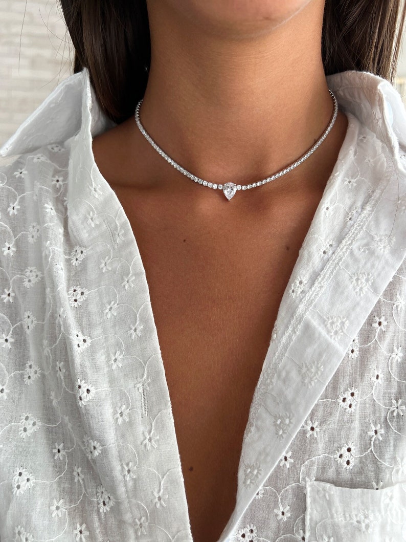 Peut inclure: Un collier ras de cou argent&eacute; avec un pendentif en diamant de forme poire.