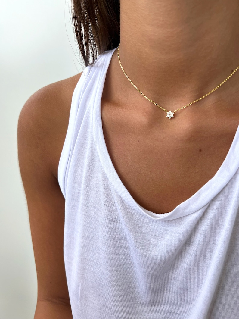 K&ouml;nnte beinhalten: Eine zarte goldene Kettenkette mit einem kleinen, funkelnden Sternanh&auml;nger.