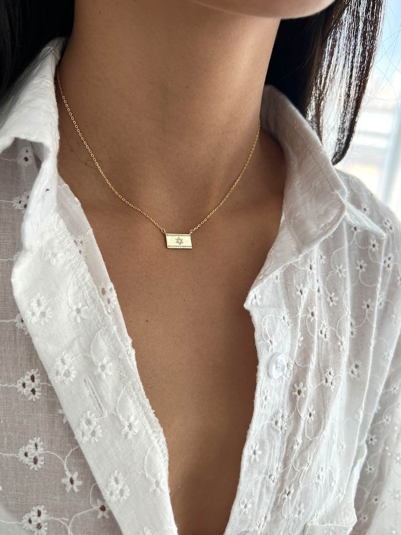 May include: A gold chain necklace with a small rectangular pendant featuring a diamond-encrusted Star of David.
