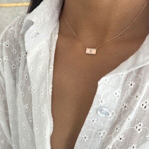 May include: A delicate gold chain necklace with a small rectangular pendant featuring a star design. The pendant is set with tiny sparkling stones.