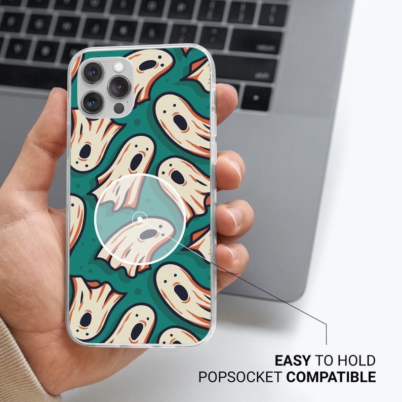 May include: Clear phone case with a green background and a pattern of white ghosts. The case is compatible with a popsocket.