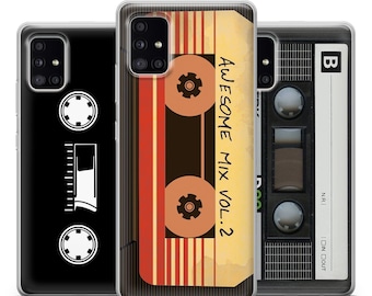 Puede incluir: Tres fundas para teléfono con un diseño de cinta de casete. La funda del centro tiene una cinta de casete roja, naranja y amarilla con el texto "Awesome Mix Vol. 2". La funda de la izquierda tiene una cinta de casete negra sobre un fondo negro. La funda de la derecha tiene una cinta de casete gris sobre un fondo gris.