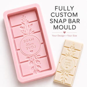 May include: A rectangular pink silicone snap bar mold featuring a floral branch design and a central circle with the text "MADE WITH LOVE" and a small heart. Next to it is a finished off-white wax bar with the same embossed design.
