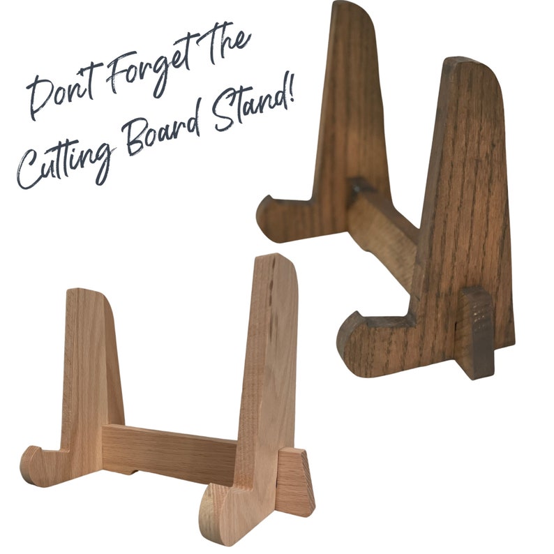 May include: Two wooden cutting board stands. One is stained dark brown and the other is natural wood. Both stands have a simple design with two upright supports and a horizontal bar connecting them. The text "Don't Forget the Cutting Board Stand!" is written in white text on a blue background.