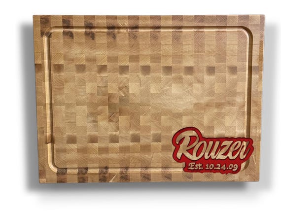 A truly large-format (24x18!) inlaid name cutting board handcrafted from premium hardwoods — this is a serious heirloom-grade piece, not a laser-etched afterthought.