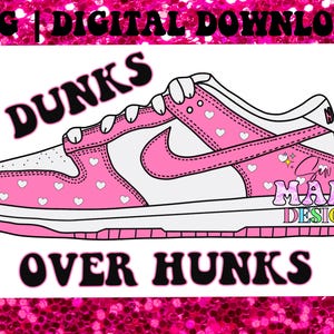 Puede incluir: Zapatillas rosas y blancas con un swoosh blanco y corazones en el lateral. El texto "Dunks Over Hunks" está escrito en letras negras debajo de las zapatillas.