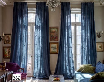 May include: A room with blue curtains framing arched windows. A chandelier hangs from the ceiling. A purple armchair and a blue sofa are visible. Artwork adorns the walls. A small wooden table is in the center of the room.