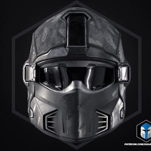 May include: A dark grey futuristic helmet with a camouflage pattern on the top. The helmet has a visor, and the text "GALACTIC ARMORY" is visible. The design includes geometric shapes and a logo.
