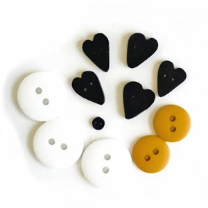 May include: Assortment of buttons in black, white, and yellow. The buttons are in various shapes, including circles and hearts.