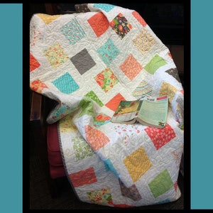 May include: A colorful quilt pattern called "Salt Water Taffy" designed by Tricia Lynn Maloney for Orphan Quilt Designs and Villa Rosa Designs. The quilt is made with a variety of fabrics in shades of pink, blue, green, yellow, and orange.