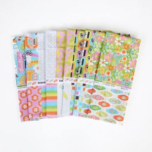 May include: A collection of colorful fabric bundles with various patterns. Designs include cameras, flowers, geometric shapes, and retro motel signs. The color palette features pink, green, yellow, and blue. Some fabrics have the text "Sunshine Inn" and "Spring 2022".